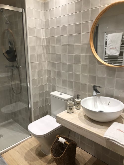 Cuarto de baño moderno en la habitación L'Isard de Casa Tapiolas, Molló con azulejos grises, espejo redondo, lavamanos tipo recipiente y ducha