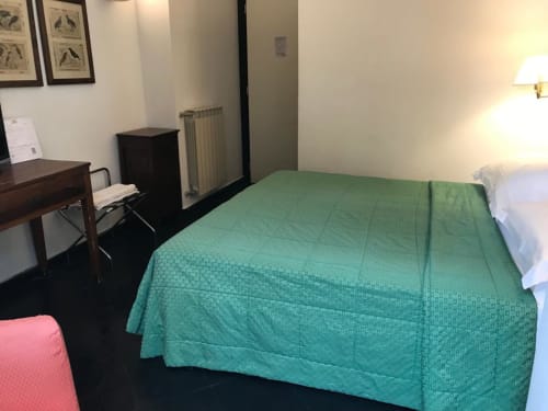 Geräumiges Schlafzimmer im Hotel Beau Rivage in Alassio mit grüner Steppdecke, Schreibtisch und Gartenblick
