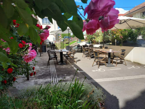 Cour du Comtois avec plantes fleuries, tables de dining, parasols et bâtiment blanc en Saône, France