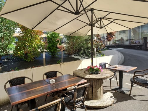Patio du Comtois BnB avec coin ombragé, tables en bois, jardinières fleuries et verdure luxuriante à Saône, France