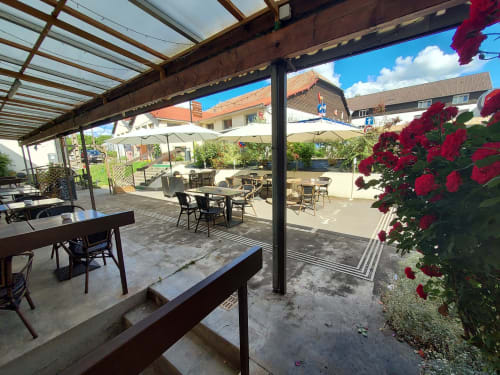 Terrasse du Comtois avec roses rouges, parasols et tables de restaurant avec vue sur la Saône, France