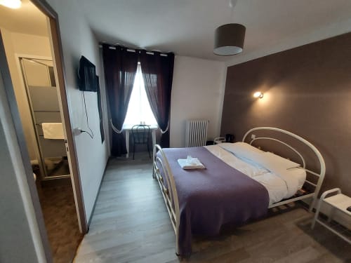 Chambre moderne au Gîte Le Comtois en Saône, France, avec lit en métal, rideaux foncés et parquet.