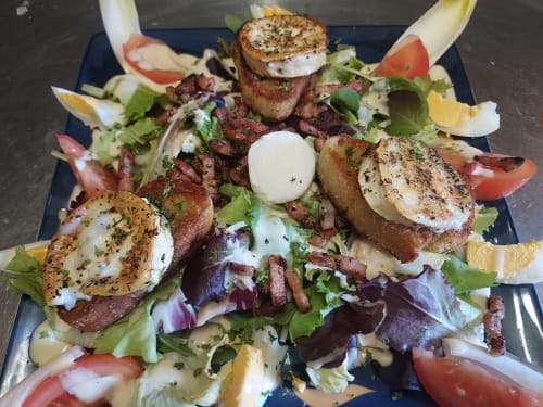 Assiette de salade gourmande aux œufs pochés, bacon et pain grillé au Comtois, Saône, France