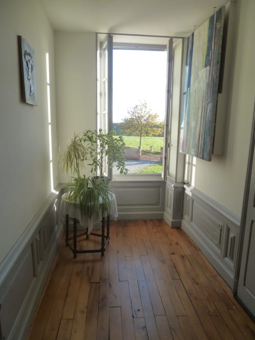 Couloir lumineux aux parquets en bois, plante en pot et portes ouvertes sur la campagne du Château De Clusors, ST MENOUX