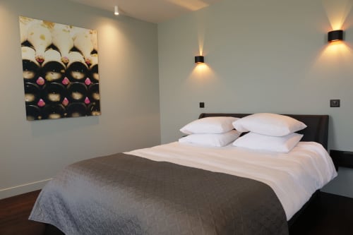 Modern bedroom at Le Petit Château with white pillows, gray bedding, wall art, and ambient lighting in Balthazar room