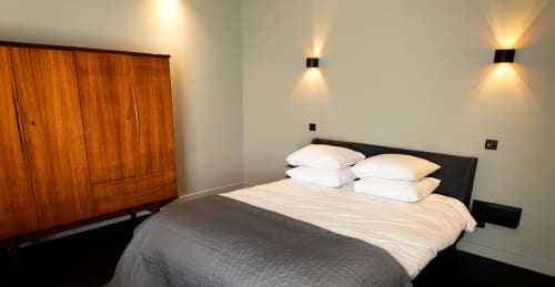 Modern bedroom at Le Petit Château B&B in Baye with queen bed, white pillows, wooden wardrobe, and ambient wall lighting