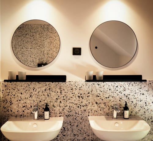 Moderne badkamer met dubbele wastafel, terrazzowastafel en ronde spiegels in het boutique hotel Le Petit Château in Baye, Frankrijk