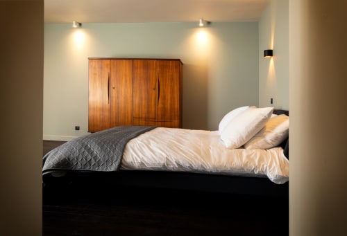Modern bedroom at Le Petit Château B&B in Baye with black bed, white pillows, wooden wardrobe, and ambient lighting