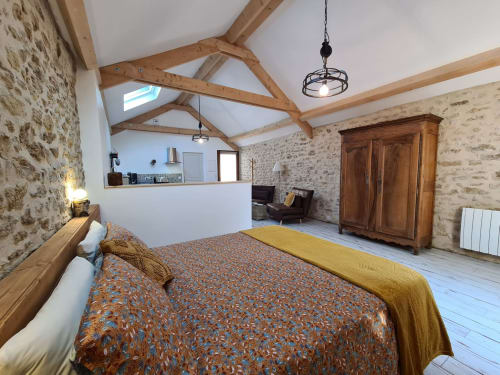 Spacious cottage bedroom at Aux Prés Du Berry with exposed wooden beams, stone walls, and modern amenities