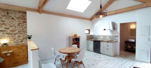 The Cowshed cottage at Aux Prés Du Berry features a bright open-plan kitchen and dining area with exposed beams and stone