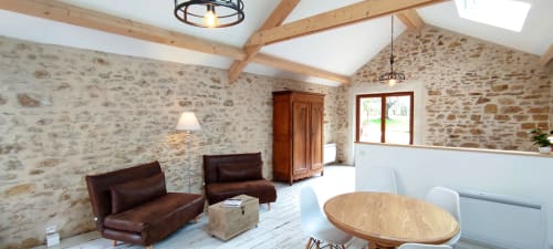 Rustic stone cottage interior at Aux Prés Du Berry with exposed beams, leather seating, and garden views