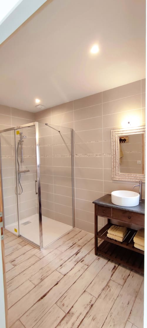 Modern bathroom at Aux Prés Du Berry cottage with walk-in shower, vessel sink, wood-look flooring, and framed mirror