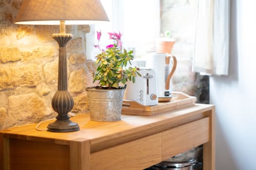 Wooden desk with brass table lamp, potted flowering plant, and white coffee maker at Espace Ker Gana B&B in Plourin, France