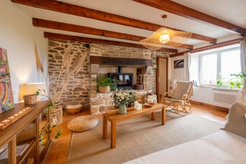 Bright living room at Espace Ker Gana in Plourin with wooden beams, stone fireplace, comfortable seating and natural light