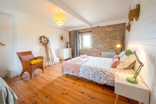 Spacious bedroom at Espace Ker Gana B&B in Plourin with wooden floor, brick wall, double bed, and modern amenities