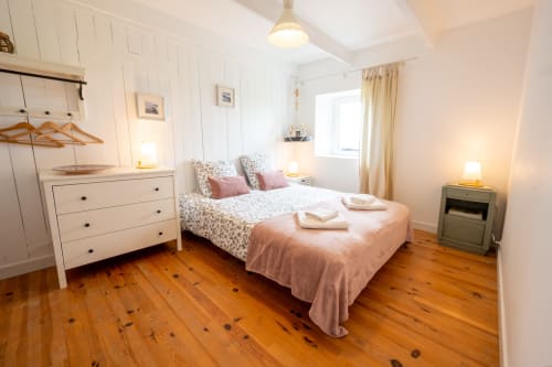 Bright bedroom at Espace Ker Gana in Plourin with wooden floors, white furniture, floral bedding, and coastal decor