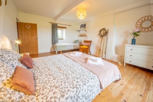 Spacious bedroom at Espace Ker Gana B&B in Plourin with two beds, wooden furniture, and warm lighting