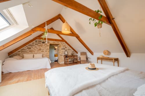 Spacious attic bedroom at Espace Ker Gana in Plourin with exposed wooden beams, two beds, stone walls and skylights