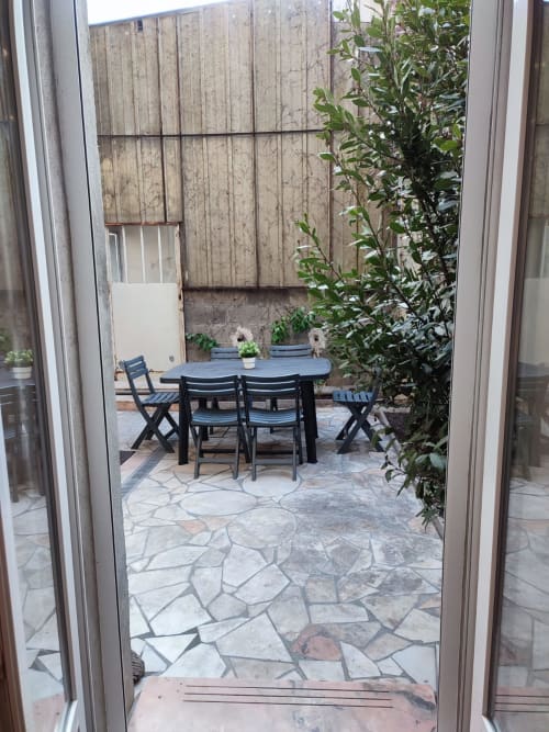 Patio privé de Lesdoucesnuits45 à Montargis avec table à manger, chaises, dallage en pierre et murets de jardin