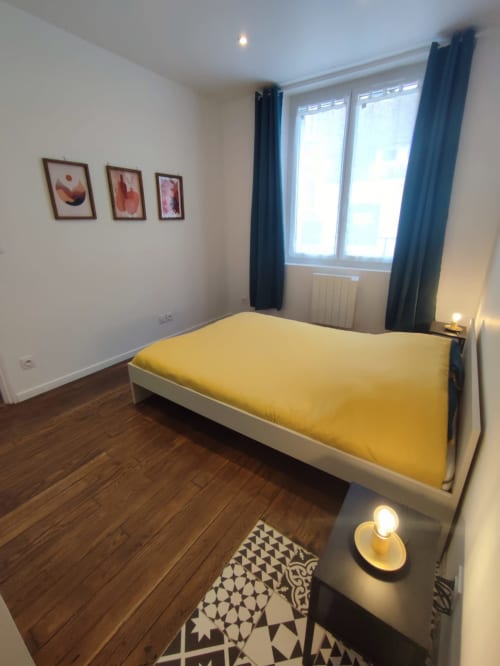 Chambre lumineuse à l'appartement Lesdoucesnuits45 à Montargis avec lit jaune, rideaux épais, parquet et vue sur la ville