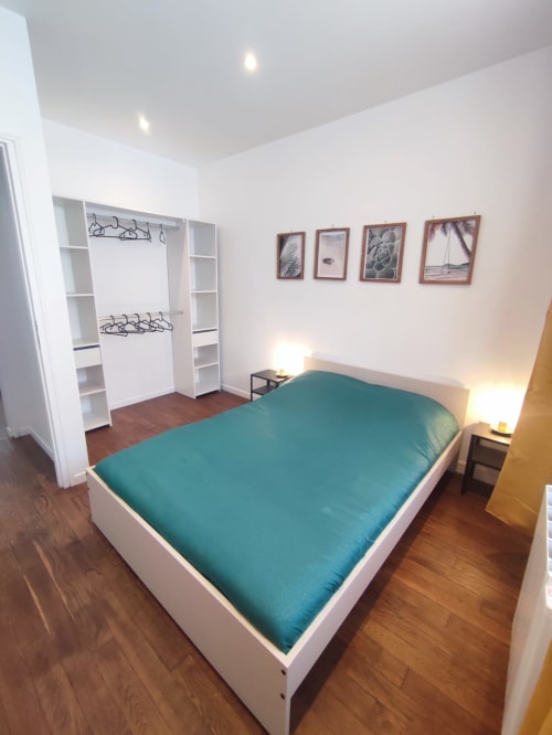 Chambre moderne à Lesdoucesnuits45 à Montargis avec literie bleu-vert, armoire blanche et vue sur la ville