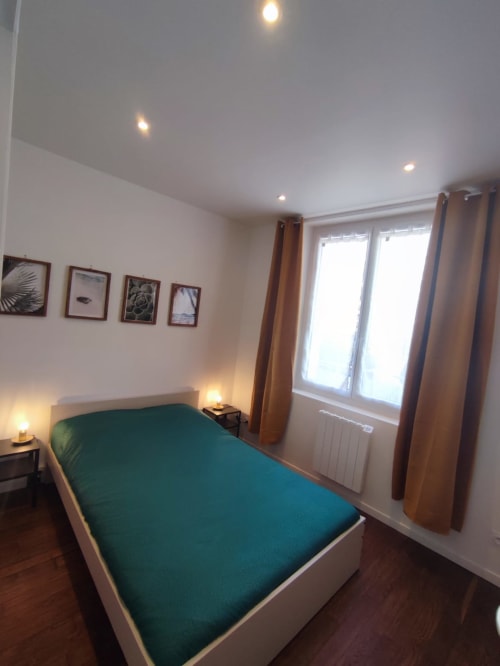 Chambre cosy à Lesdoucesnuits45 à Montargis avec literie verte, éclairage moderne et rideaux marron