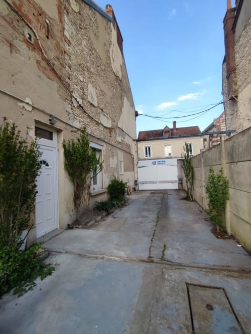 Ruelle étroite de l'appartement Lesdoucesnuits45 à Montargis, France, avec ses bâtiments en pierre traditionnels et entrée sur cour.