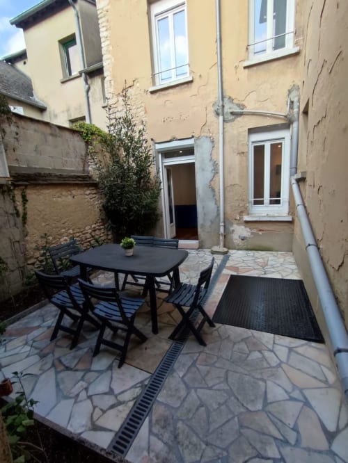 Cour privée de Lesdoucesnuits45 à Montargis avec table de salle à manger noire, chaises et dallage en pierre
