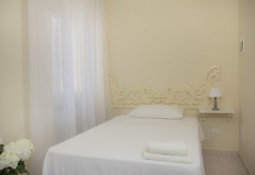Camera da letto luminosa presso Il Linchetto B&B a Lucca con biancheria bianca, testata ornamentale e luce naturale dalle finestre