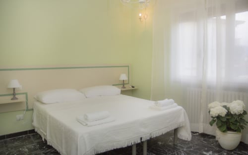 Camera luminosa a Il Linchetto B&B di Lucca con letto bianco, pareti verdi, lampade comodino 