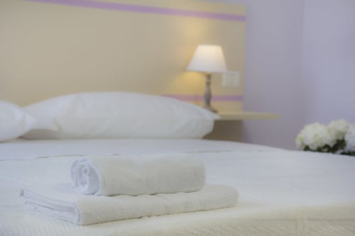 Camera lussuosa a Il Linchetto B&B Lucca con asciugamani bianchi arrotolati, cuscino, lampada e fiori 