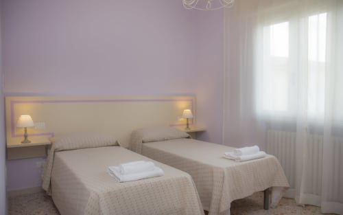 Camera superior dell'Il Linchetto B&B a Lucca con letti gemelli, o letto matrimoniale, pareti viola, lampade comodino e luce naturale dalle finestre