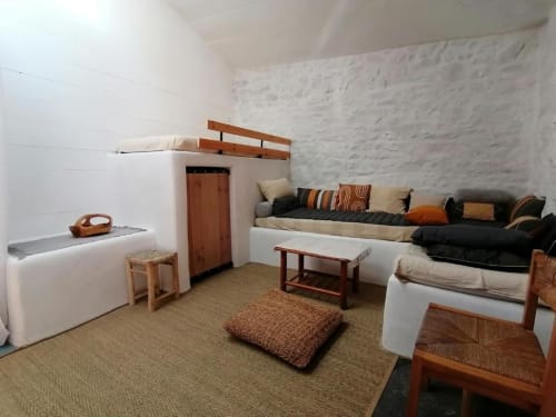 Chambre sur pilotis Furanelle à Saint-Etienne avec lits en bois, coussins rayés, tapis tissé et mobilier rustique