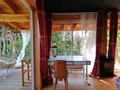 Espace de travail en bois avec bureau et chaise dans la Chambre pilotis de Furanelle, vue forêt depuis le balcon, Saint-Etienne