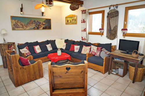 Acogedor salón en L'étape Du Fanfoué en Chamrousse con muebles de madera, sofá azul marino y decoración alpina