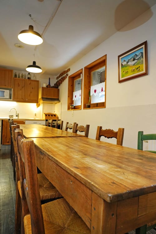 Comedor rústico en L'étape Du Fanfoué en Chamrousse con mesas de madera, sillas vintage y arte de montaña