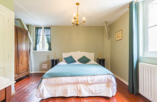 Chambre élégante au Manoir Le Coutureau avec literie bleue, tête de lit crème et parquet donnant sur le jardin