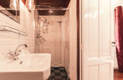 Salle de bain moderne du Manoir Le Coutureau avec carrelage métro blanc, douche vitrée, lavabo sur colonne et porte-serviettes rouge