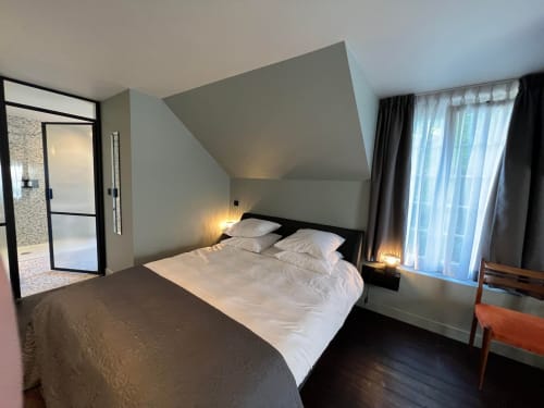 Chambre moderne au Petit Château avec lit queen, plafond mansardé, salle de bain attenante, grandes fenêtres avec vue sur le jardin et