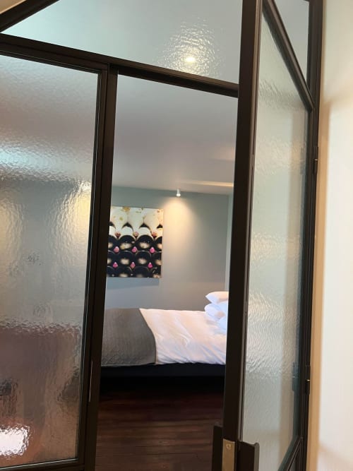 Balthazar kamer in Le Petit Château B&B in Baye, Frankrijk, gezien door gerookt glazen deuren met bed met witte kussens