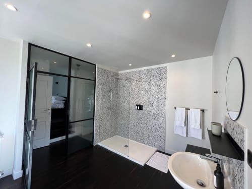 Modern bathroom in Le Petit Château with walk-in shower, freestanding tub, and dark flooring