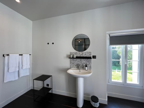 Modern bathroom in Salomon room at Le Petit Château B&B featuring pedestal sink, circular mirror, and garden view through