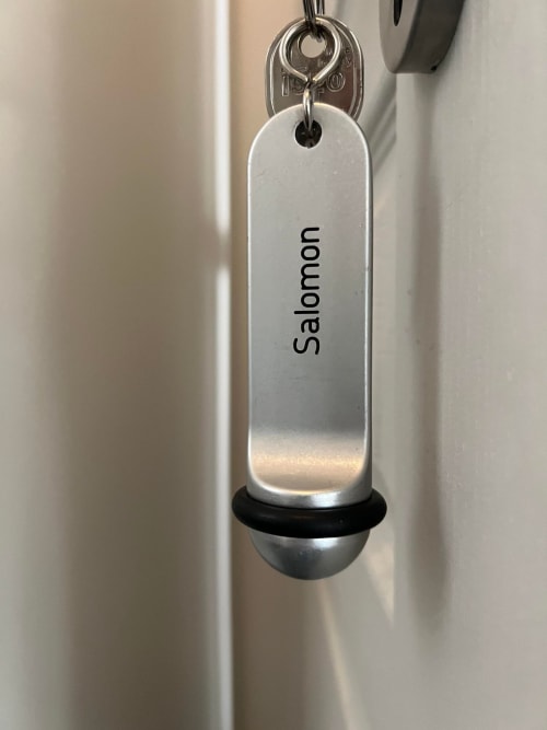 Metal keychain with 'Salomon' engraved, hanging from hotel key at Le Petit Château BnB in Baye, France