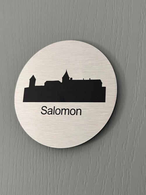 Salomon room sign at Le Petit Château bed and breakfast in Baye, France featuring castle silhouette on circular wooden plaque