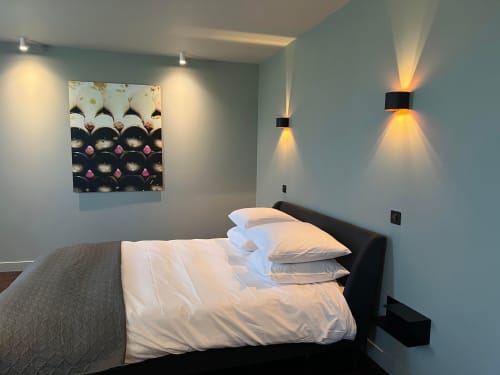 Moderne slaapkamer in Le Petit Château met wit beddengoed, wandlampen en bloemenschilderijen in Baye, Frankrijk
