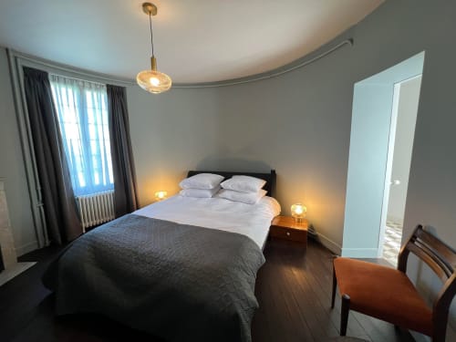 Moderne slaapkamer in Le Petit Château met tweepersoonsbed, hangende verlichting en uitzicht op de tuin vanuit het raam