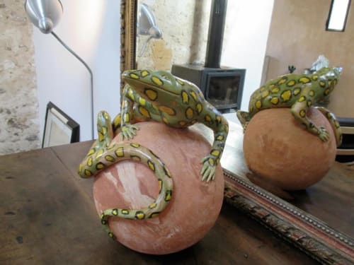Grenouilles décoratives en céramique aux motifs jaunes pointillistes, perchées sur des sphères en terre cuite dans le jardin de l'appartement Le Mas du Fort