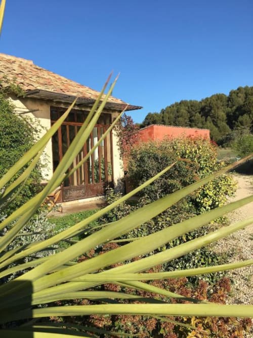 Vue du jardin du Mas du Fort avec agaves, maison rustique et terrasse à Gargas
