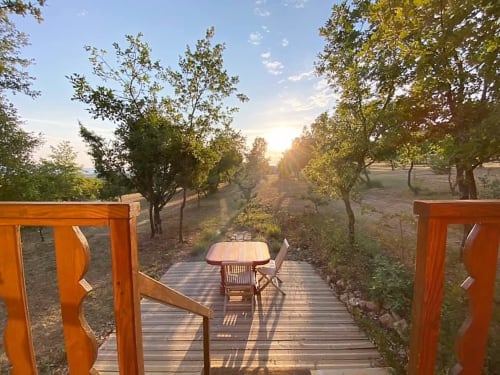 Terrasse en bois avec table à manger surplombant la campagne bordée d'arbres au Mas du Fort à Gargas, France