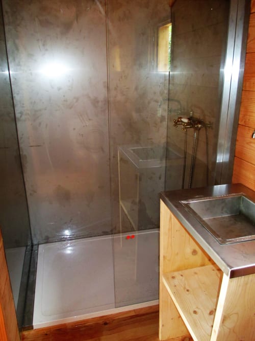 Salle de bain moderne avec douche vitrée et meuble en bois du gîte Le Mas du Fort, Gargas